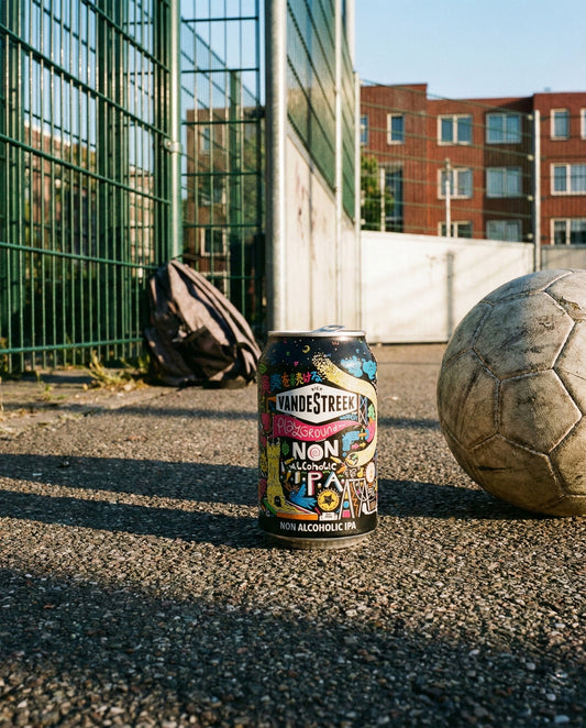 Vandestreek Playground can on Dutch street football cage asphalt at golden hour with worn ball and rucksack
