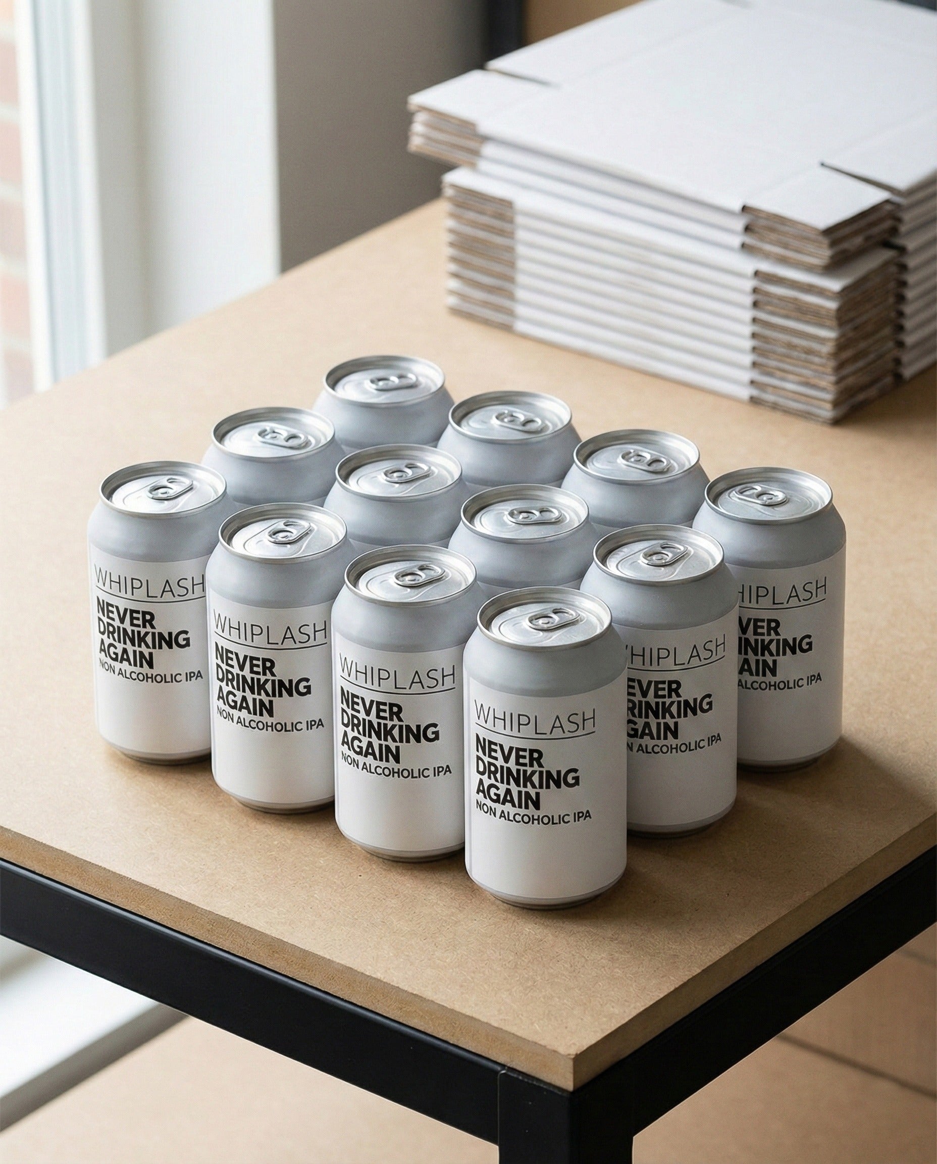 Twelve Whiplash Never Drinking Again cans in a cardboard shipping tray on raw MDF